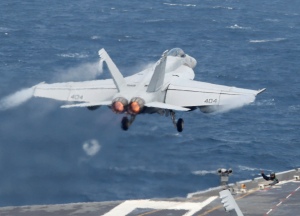 A crew member guides a U.S. Navy F/A-18 Super Hornet fighter taking off from the deck of U.S. aircraft carrier USS George Washington during joint military drills between the U.S. and South Korea in the West Sea